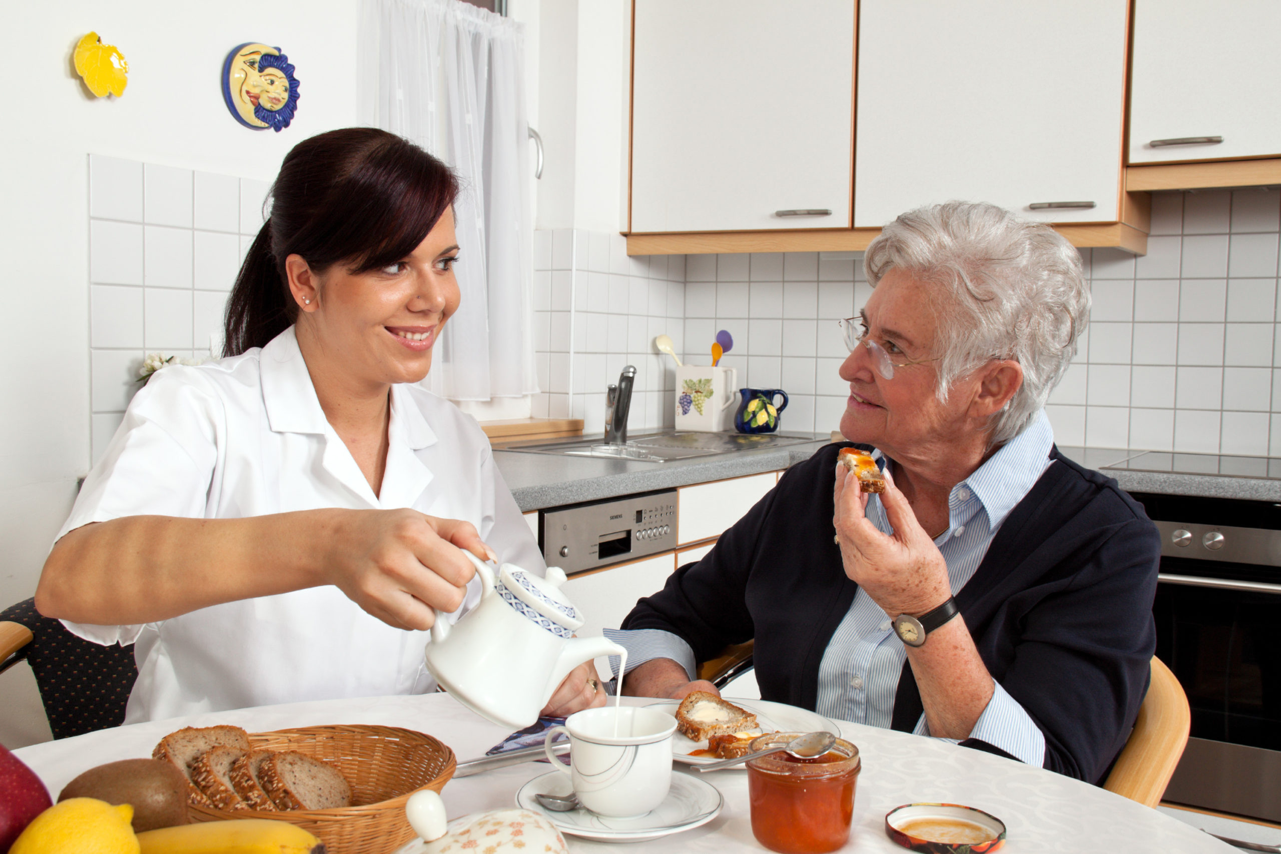 caregiver helping elderly woman with breakfast